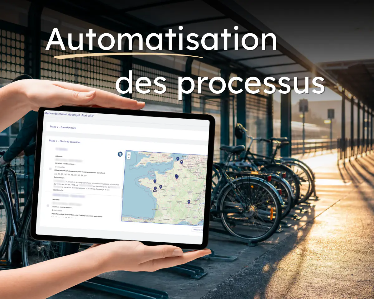 « Automatisation des processus » : une tablette affiche un parcours d’instruction de dossier avec sa carte de France des conseillers, devant un abri à vélos de gare.