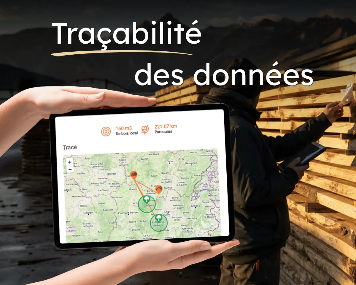 « Traçabilité des données » : une tablette affiche le tracé cartographique d’un approvisionnement en bois local et les kilomètres parcourus, devant les piles de sciages d’une scierie de montagne.